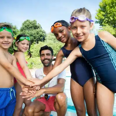 Kids and coach stacking hands before competition